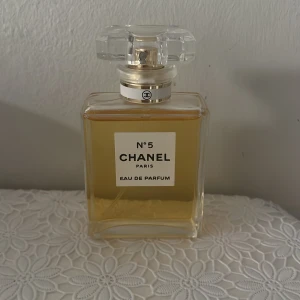 Chanel No. 5 Eau de Parfum - Elegant och tidlös parfym från Chanel i en klassisk fyrkantig glasflaska med en stilren etikett. Doften är ikonisk och sofistikerad, perfekt för den som vill ha en touch av lyx i vardagen. Flaskan har en genomskinlig kork som ger en exklusiv känsla. Endast provad en gång.