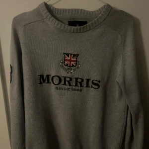 Grå tröja från Morris - Snygg grå tröja från Morris med ett broderat emblem och text på framsidan. Tröjan har långa ärmar och ett stilrent nummer 8 på ärmen. Perfekt för en casual look. Riktigt snygg till sommaren och våren! Priset kan diskuteras‼️‼️