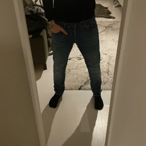 Blå jeans från Jack and Jones  - Snygga blå jeans med en klassisk passform. De har en normal midja och raka ben, vilket ger en tidlös look. Perfekta för en avslappnad stil. W31 L32. Har en liten defekt darför jag säljer billigt men annars i toppen skick.  Kolla min profil för billiga bra deals för jeans och piké tröjor🔥🔥🔥. Hör av er med minsta fundering👍