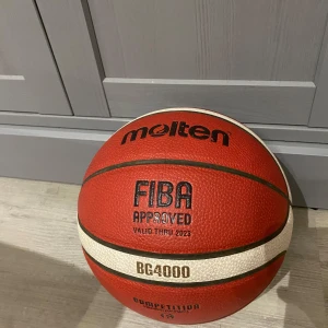 Basketboll Molten BG4000 - Säljer en Molten BG4000 basketboll, FIBA-godkänd. Perfekt för tävlingsspel med sin slitstarka yta och utmärkta grepp. Bollen har en klassisk röd och vit design med tydliga svarta linjer. Har lite utsuddat namn på sig som säkert går att få bort om man försöker, produkten är knappt använd och en dyr version, orginalpris 400kr