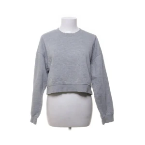 Grå croppad sweatshirt - Säljer en stilren grå croppad sweatshirt med långa ärmar. Perfekt för en avslappnad look. Passar bra till jeans eller leggings.