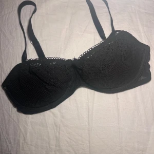 Svart spets-bh - Säljer en elegant svart bh med spetsdetaljer. Den har justerbara axelband och en klassisk hakknäppning bak. Perfekt för en stilren look. Liten i stoleken ‼️Knappt använt den och köpte för 649kr.