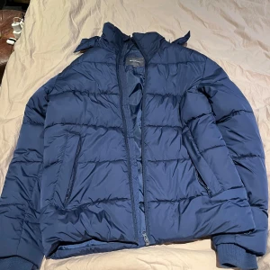 Blå pufferjacka - Säljer en blå pufferjacka med dragkedja och ribbade muddar. Märke: Dressman. Storlek: S men passar M. 