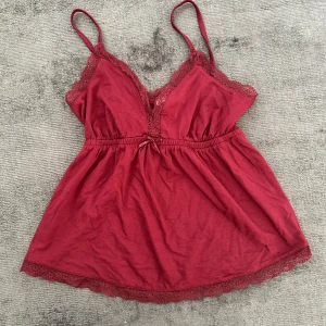 Vinröd spetstopp från Nelly -  En söt vinröd topp från Nelly med spetsdetaljer och smala axelband. 