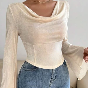 Beige långärmad topp - Säljer en elegant beige långärmad topp med draperad design. Perfekt för en stilren look. Materialet är mjukt och följsamt.