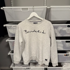 Vit tröja från Bondelid - Säljer en stilren vit tröja från Bondelid med ett diskret mönster och broderad logga på framsidan. Tröjan har långa ärmar och ribbade muddar vid ärmslut och nederkant. Storlek L