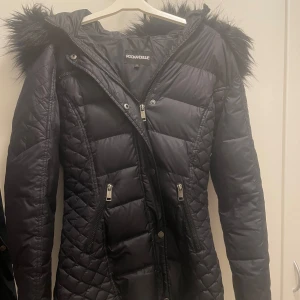 Rockandblue jacka - Snygg svart dunjacka från Rockandblue med quiltad design och pälskantad huva. Fickorna är dock sönder, går att sy.