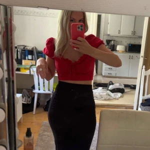 Röd croppad topp med puffärmar - Trendig röd croppad topp med puffiga kortärmar och en söt knytdetalj framtill. Perfekt för en somrig look eller en utekväll. Toppen har en smickrande passform och är tillverkad i ett mjukt material.