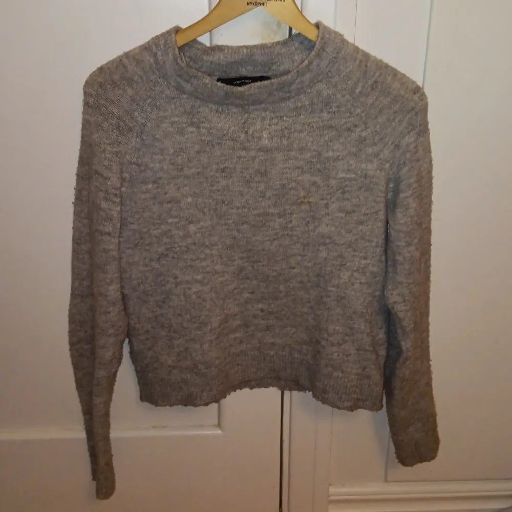 Mysig grå stickad tröja från Vero Moda. Perfekt för kyliga dagar med sin klassiska design och bekväma passform. Tröjan har långa ärmar och en rund halsringning.. Neuletakit & Villapaidat.