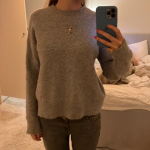 Grå stickad tröja - Mysig grå stickad tröja med långa ärmar och ribbade muddar. Perfekt för kyligare dagar och enkel att matcha med olika outfits.