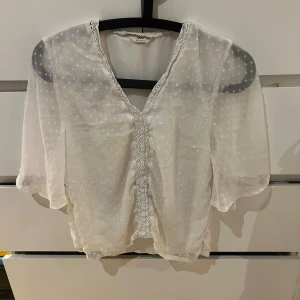 Vit blus från ONLY - Säljer en söt vit blus från ONLY i storlek XS. Blusen har ett prickigt mönster och v-ringad design med spetsdetaljer. Den är kortärmad och perfekt för vår och sommar. köpte den för 349kr säljer den för 135+frakt.