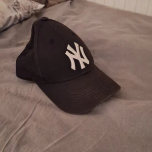 Svart keps med vit broderad logga - Snygg svart keps med en vit broderad logga framtill. Justerbar rem baktill för perfekt passform. Perfekt för en avslappnad stil.