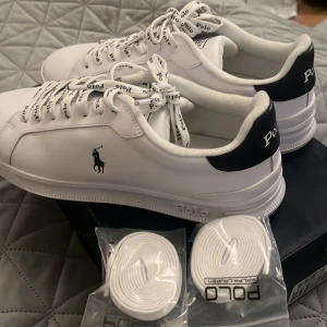 Vita sneakers från Polo Ralph Lauren - Snygga vita sneakers från Polo Ralph Lauren med klassisk design. Skorna har en mörkblå detalj vid hälen och logga på sidan. De kommer med ralph lauren märkes snören och extra par vita snören i förpackning. Endast använda 3 gånger. Säljer då de inte kommer till användning. Pris går att diskuteras