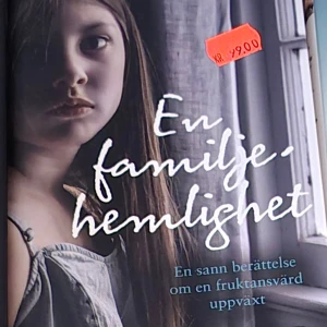 En familjehemlighet - Boken 'En familjehemlighet' är en gripande sann berättelse om en fruktansvärd uppväxt. Omslaget visar en ung flicka med allvarlig blick, vilket speglar bokens tunga tema.