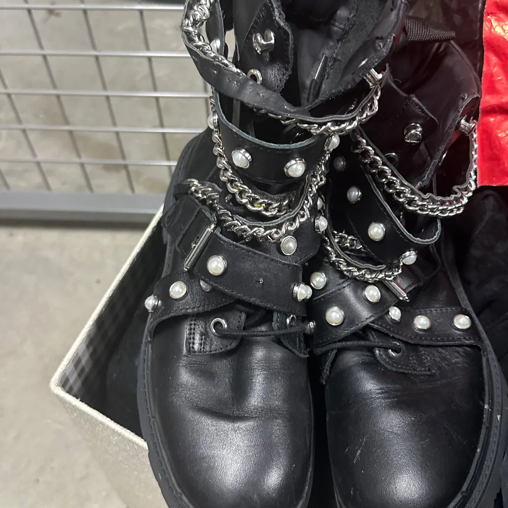 Snygga svarta boots med dekorativa kedjor och pärlor. Skorna har snörning och en robust design som ger en edgy look. Perfekta för att ge din outfit en unik touch. Äkta läder från zara stl 38. Kengät.