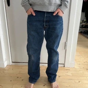 Levis 501 jeans - Klassiska Levis 501 jeans i en snygg blå färg. De har en rak passform och är tillverkade i slitstarkt denim. Perfekta för en avslappnad stil. Personen på bilderna är 160 cm lång, 12 år gammal och har en smal/normal kroppsbyggnad.  Skick: Mycket bra begagnat skick.  Nypris: 999 SEK