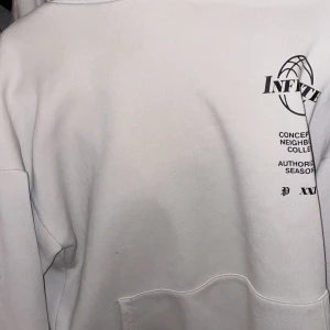 Beige hoodie med tryck från Infinite - Säljer en beige hoodie från Infinite med coolt tryck av en brinnande basketkorg. Hoodien har en avslappnad passform och är perfekt för en casual look. Den har långa ärmar och en klassisk huva.