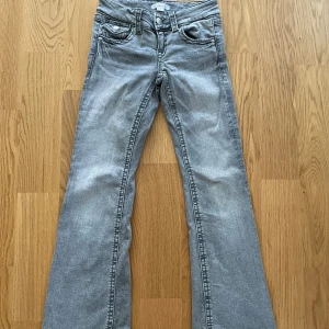Chunky low flare jeans från Gina Tricot - Säljer ett par snygga grå jeans från Gina Tricot i storlek 146. De har en klassisk femficksdesign med knappar och dragkedja framtill. Jeansen har en bootcut-stil som ger en skön retrovibe. Perfekta för både vardag och fest!