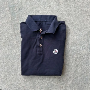 Moncler piké  - Snygg moncler piké i mörkblå. Väldigt bra skick. Storlek S men kan passa M beroende på hur man vill att den ska sitta  Nypris: 3499 Mitt pris: 399