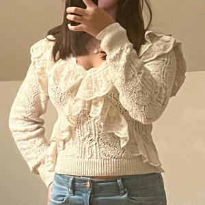 Vit stickad tröja med volangdetaljer - Säljer en superfin vit stickad tröja med volangdetaljer. Tröjan har långa ärmar och en tight passform som framhäver figuren. Perfekt för höst och vinter, den är både varm och stilren. Passar bra till både jeans och kjol. 🧡