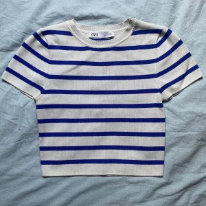 Randig kortärmad topp från Zara - Säljer en superfin randig topp från Zara i storlek s. Den är vit med blå ränder och har en ribbad struktur. Toppen är kortärmad och croppad, den är i nyskick och nypris 200 🌟