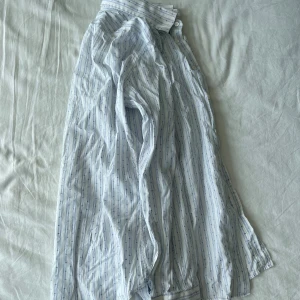 Vit och blå randig skjorta från Paul & friends - Säljer en stilren vit skjorta med blå ränder och prickar från Paul & friends. Skjortan är långärmad och tillverkad i Italien. Perfekt för både vardag och festliga tillfällen. Den är i storlek M och har en klassisk krage med knappar framtill.