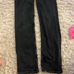 Svarta jeans från Pull&Bear - Säljer ett par svarta jeans från Pull&Bear. De har en klassisk design med dragkedja och knapp framtill. Jeansen har en rak passform och är perfekta för både vardag och fest. De är i bra skick och redo för en ny ägare!