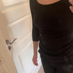 Svart långärmad topp - Säljer en stilren svart topp med trekvartsärm. Perfekt för både vardag och fest. Toppen har en tight passform och är gjord i ett mjukt och bekvämt material.