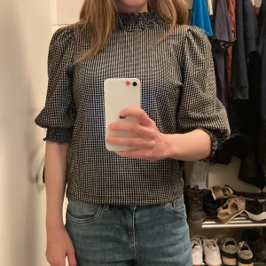 Topp - Puffärmad topp Rutigt mönster Färger: svart och vit  40 maskintvätt 99% polyester 1% elastan