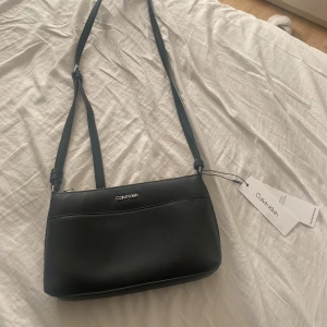 Handväska/väska  - Helt ny väska ifrån Calvin Klein med prislapp. Aldrig använd i ny skick, går att justera längden på bandet. Pris kan diskuteras 