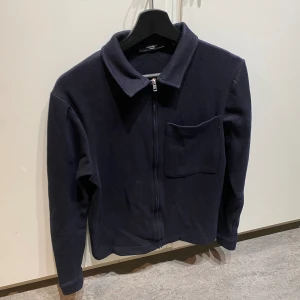 Helzip med krage - Mörkblå helzip tröja med krage. Använd ett fåtal gånger och är i nytt skick. Tröjan är den Jack and Jones. Storlek är S men passar XS då den är liten i storleken.