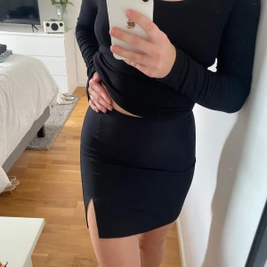 Svart kjol från NA-KD - Säljer denna supersnygga kjol från NA-KD i storlek 34. Kjolen har en tight passform och en liten slits framtill som ger en snygg detalj. Perfekt för både vardag och fest! 🖤Säljer den då den tyvärr är för liten för mig.