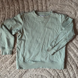 Ljusgrön collegetröja - lager 157 [storlek 150] - Säljer en ljusgrön collegetröja från lager 157. Tröjan har långa ärmar och en rund halsringning med ribbade muddar vid ärmslut och nederkant. Perfekt för en avslappnad look. Material: 100% bomul