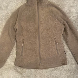 Beige fleecejacka  - Mysig beige fleecejacka från lager 157 med dragkedja framtill och två praktiska fickor med dragkedjor. Perfekt för kyliga dagar och ger en skön och varm känsla. Jackan har långa ärmar och en hög krage för extra värme❣️❣️❣️