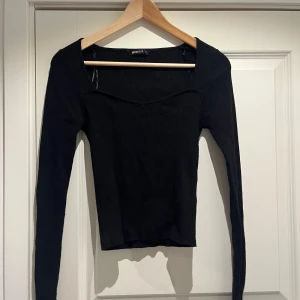 Svart ribbad tröja från Gina Tricot - Säljer en stilren svart ribbad tröja från Gina Tricot. Tröjan har en elegant fyrkantig halsringning. Jag har sytt igen armarna längst ned
