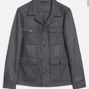 Oscar jackobson overshirt  - Snygg grå overshirt med knappar och fyra fickor framtill. Perfekt för lager-på-lager-stil. Den har en klassisk krage och långa ärmar, vilket gör den idealisk för kyligare dagar.