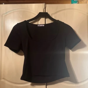 Svart kortärmad topp från Zara - Säljer en stilren svart topp från Zara med korta ärmar och en rundad halsringning. Perfekt för en enkel och elegant look.