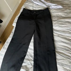 Svarta kostymbyxor från Bik Bok - Snygga svarta kostymbyxor från Bik Bok i storlek 38. De har en klassisk design med raka ben och bälteshällor. Perfekta för en stilren look. Heter maddie 