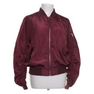 Vinröd bomberjacka  - Snygg vinröd bomberjacka från Hva by Havana i 100% polyester. Säljer då den aldrig kom till användning!!