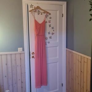 Rosa långklänning från Gina Tricot - Säljer en rosa långklänning från Gina Tricot. Klänningen har smala axelband och en vacker, flytande design som passar perfekt för sommarens festligheter. Den är tillverkad i ett lätt och bekvämt material. 