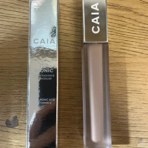 CAIA its Iconic Concealer - Säljer en CAIA True Iconic Concealer med hyaluronsyra och vitamin C. Den kommer i en elegant förpackning med silverlock och är perfekt för att dölja ojämnheter och ge en strålande hy. Endast testad. 3C
