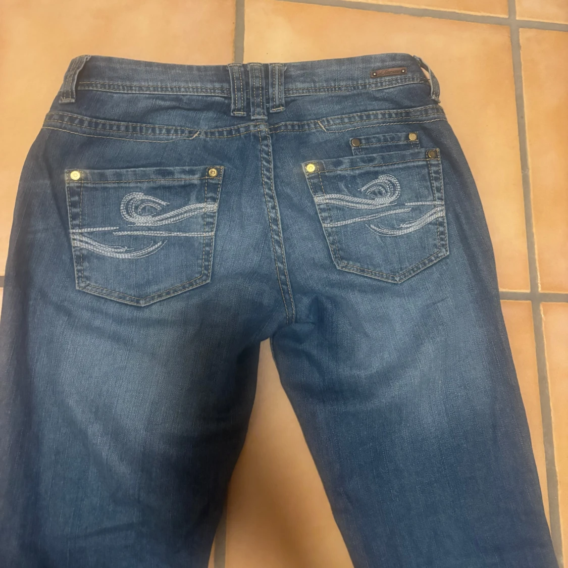 Blå jeans med tryck på bakfickan