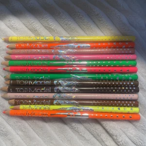 Färgglada pennor från Top Model - Säljer ett set med färgglada pennor från Top Model. Pennorna kommer i olika nyanser som rosa, grön, brun och orange. Perfekt för att skapa kreativa och unika bilder. Varje penna har ett glittrande mönster och är lätt att använda för fantastiska målningar. De är vintage och från många år sedan.
