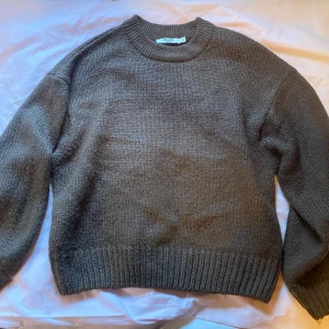 Brun stickad tröja från NA-KD - Säljer en snygg brun stickad tröja från NA-KD. Tröjan har en klassisk rund halsringning och ribbade muddar vid ärmslut och nederkant. Perfekt för kyliga dagar! 🍂