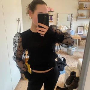 Svart tröja med transparenta ärmar från May by Shining Star - Snygg svart tröja med transparenta ärmar i mesh och prickigt mönster. Stolek S/XS. 60kr🖤