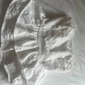 Vit blommig offshoulder topp - Säljer en söt vit offshoulder topp med blommigt mönster som man knyter en söt rosett där bak💕💕trots att den är från Shein skulle jag säga att den är väldigt bra kvalitet på materialet! 