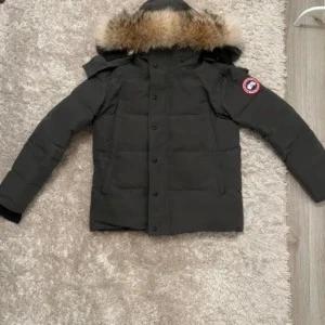 Svart dunjacka med pälsdetalj - Säljer en svart dunjacka från Canada Goose med pälsdetalj på huvan. Jackan har långa ärmar och knappar framtill. Perfekt för kalla dagar.