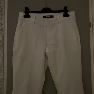 Vita kostymbyxor från BikBok - Säljer dessa fina kostymbyxor från Bikbok som har slit. Dem är i storlek 34 och är i modellen ”vera petite”. Dem är lite lite långa för mig som är 155cm. Dem har en liten fläck under vänster ficka och en liten liten bak under fickan. Köpta för 400kr. Pris kan diskuteras🌸