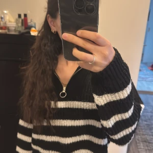 Svart och vit randig tröja med dragkedja - Säljer en svart och vit randig tröja med dragkedja framtill. Tröjan har långa ärmar och är perfekt för en avslappnad stil. Den är både bekväm och stilren.