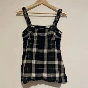 Rutig linne i svart och vitt - Snygg rutig linne i svart och vitt med breda axelband. Perfekt för en avslappnad stil. Den har en klassisk rutdesign som ger en tidlös look.